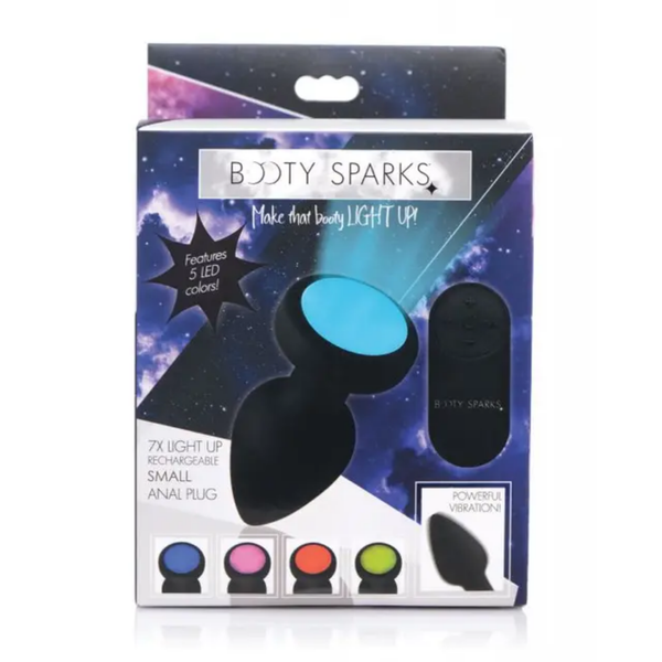 Retail box packaging view for the Booty Sparks 7x Light Up Rechargeable Small Anal Plug featuring galaxy-themed graphics, remote control callout, and 5 LED color option previews.