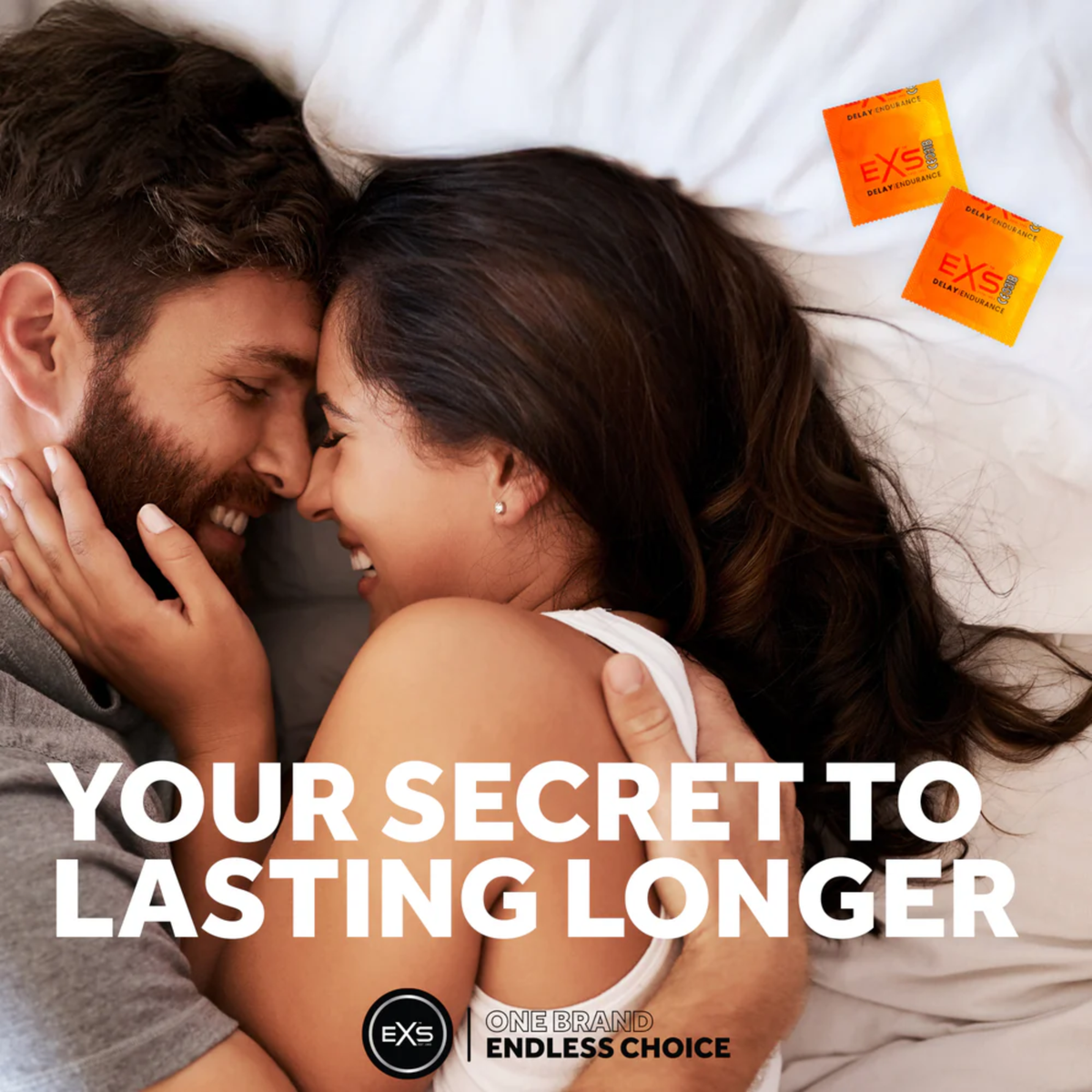 Lifestyle photograph of a smiling couple embracing closely in bed. Bold overlay text reads "YOUR SECRET TO LASTING LONGER," accompanied by two orange EXS Delay Endurance condom wrappers in the upper corner.