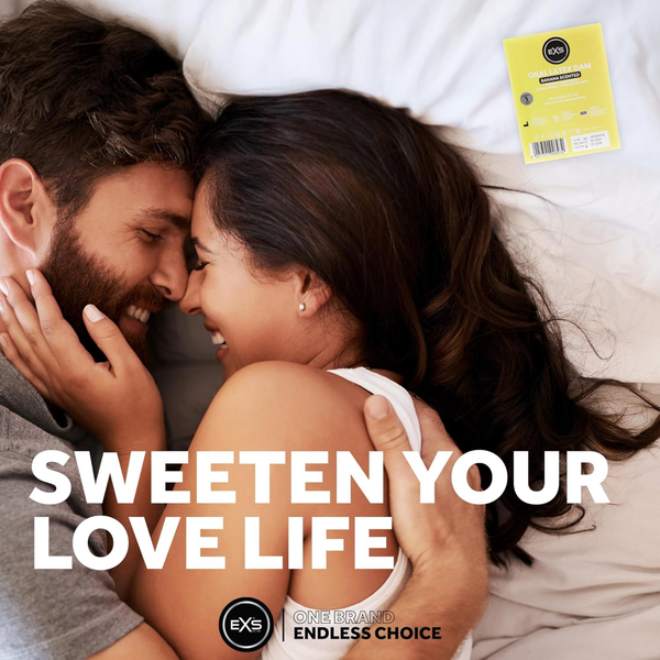 Lifestyle image of a smiling couple embracing closely in bed. Bold text overlay reads "SWEETEN YOUR LOVE LIFE," accompanied by a single-pack EXS Banana Scented Oral Latex Dam in the upper right corner.