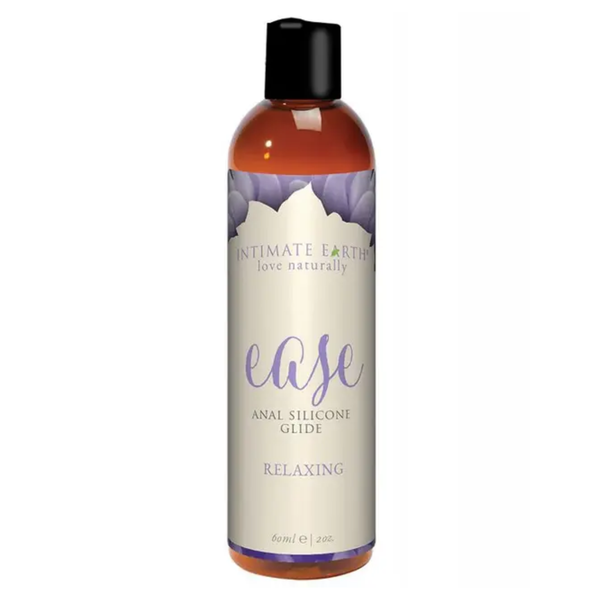 Front product view of the compact 60 ml (2 fl oz) amber bottle of Intimate Earth Ease relaxing anal silicone glide with purple petal design accents.