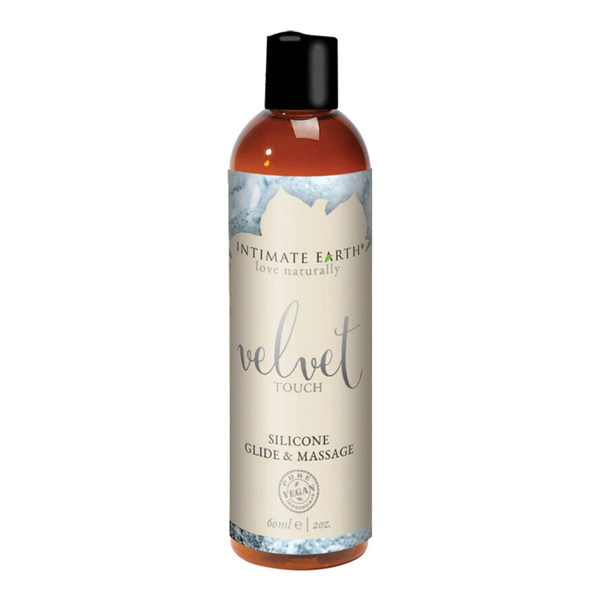 Front studio view of the compact 60 ml (2 fl oz) amber bottle of Intimate Earth Velvet Touch silicone glide & massage oil with a black disc cap and pure vegan seal.