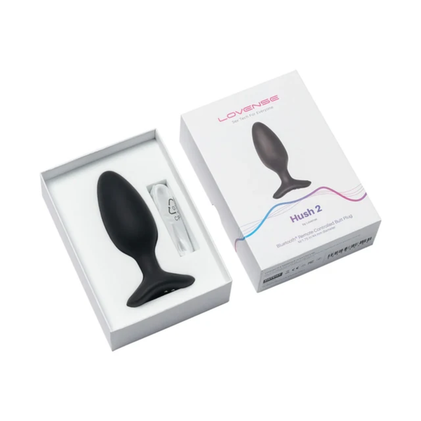 Unboxing perspective photo showing the black Lovense Hush 2 butt plug and charging cable inside the open white box base alongside the box lid.