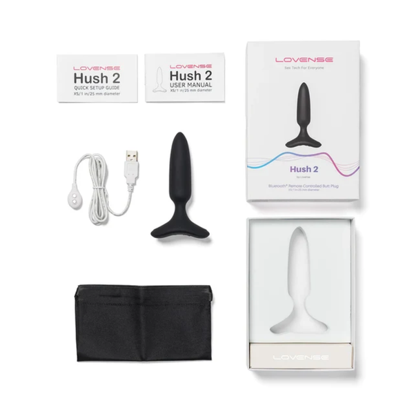 Flat-lay collection shot displaying the 1-inch Lovense Hush 2 butt plug, box, user manual, quick setup guide, USB charging cable, satin storage pouch, and inner packaging tray.
